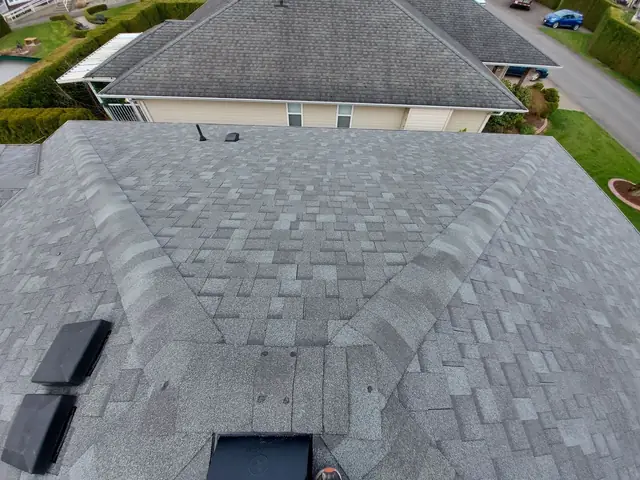 Completed architectural asphalt shingle roof installation on residential home with multiple roof planes showing professional finish and clean design.