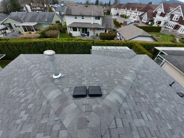 Professional gray architectural asphalt shingle roof installation showing clean finish and proper shingle placement on multi-plane residential roof with mountain views.