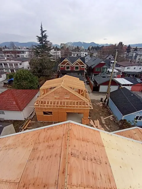 Aerial view of new roof framing structure during construction with mountain views and residential buildings visible in Chilliwack area.