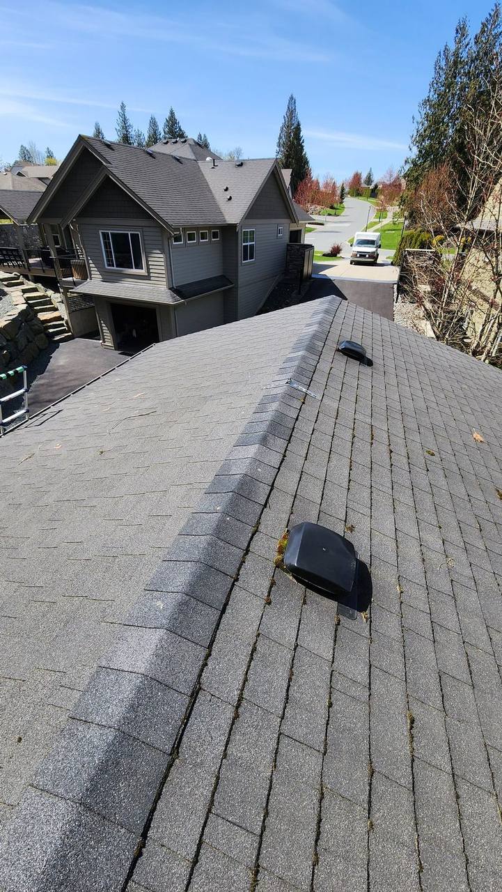 Completed charcoal gray shingle roof by Fraser Roofing Fraser Valley BC showing ridge cap and vent installation