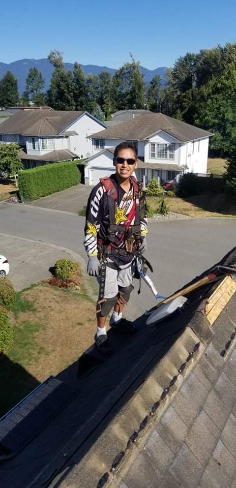 Kory Peters, founder of Fraser Roofing, standing on a residential roof in full safety harness with Fraser Valley mountains behind him in Agassiz BC