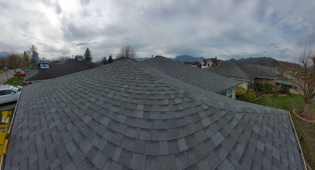 Completed charcoal architectural asphalt shingle roof installation viewed from ridge peak in the Fraser Valley, the finished result that represents the quality craftsmanship your roofing investment buys