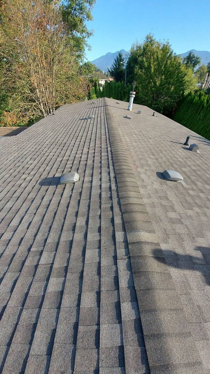 Completed ridge cap installation on asphalt shingle roof with Fraser Valley mountain views by Fraser Roofing
