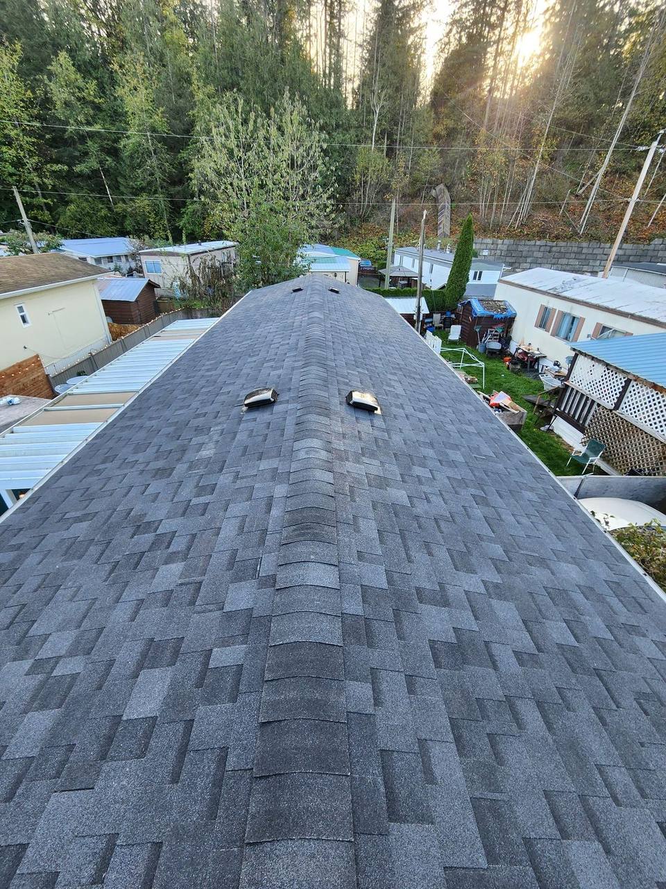 Completed gable roof with charcoal architectural shingles viewed from the ridgeline in the Fraser Valley, valley and ridge work that adds real curb appeal and property value