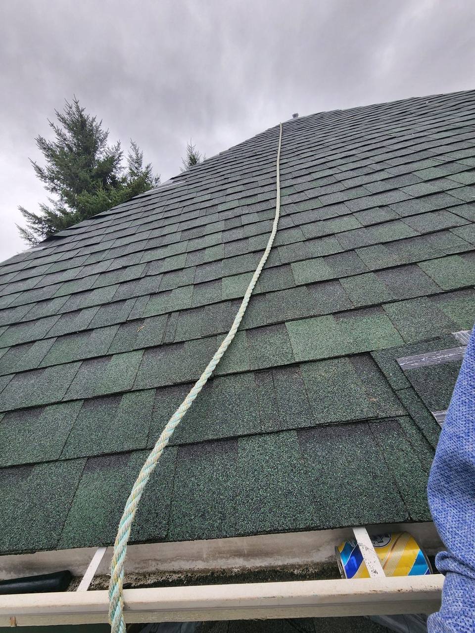 Fraser Roofing crew inspects an aging green 3-tab asphalt shingle roof in the Fraser Valley with safety rope running from eave to ridge during a September 2023 assessment.