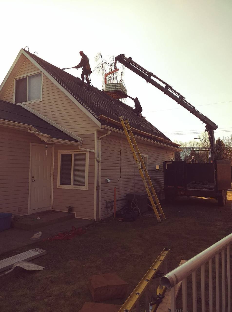 The Fraser Roofing team uses a hydraulic knuckle boom crane during a residential roof operation in the Fraser Valley, for major storm damage and large debris removal, professional equipment and crew coordination make the difference.