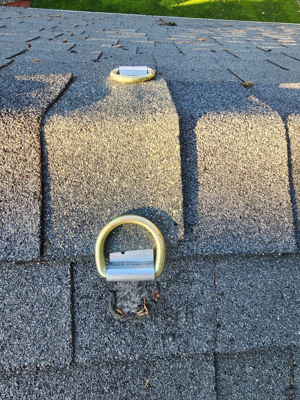 Roof safety D-ring anchor point installed on asphalt shingles for fall protection during roofing work