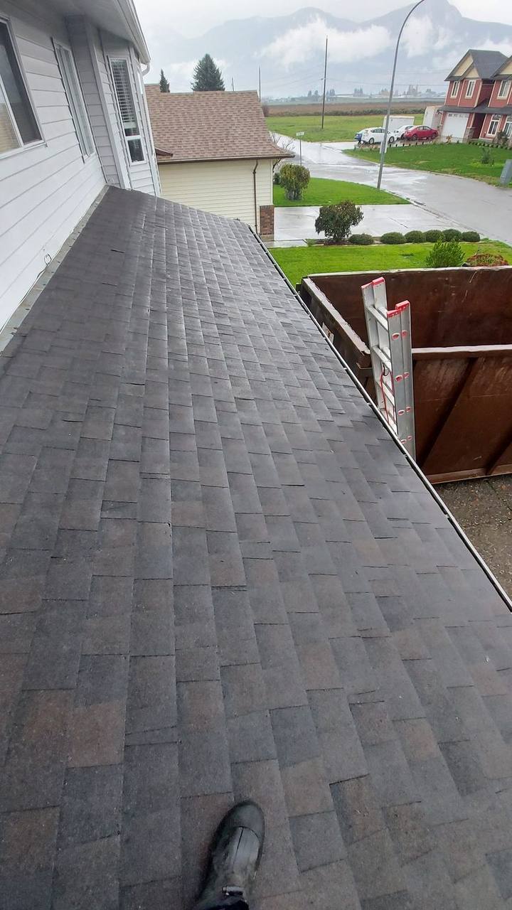 Completed charcoal asphalt shingle roof section on Chilliwack BC home with drip edge and Fraser Valley mountains