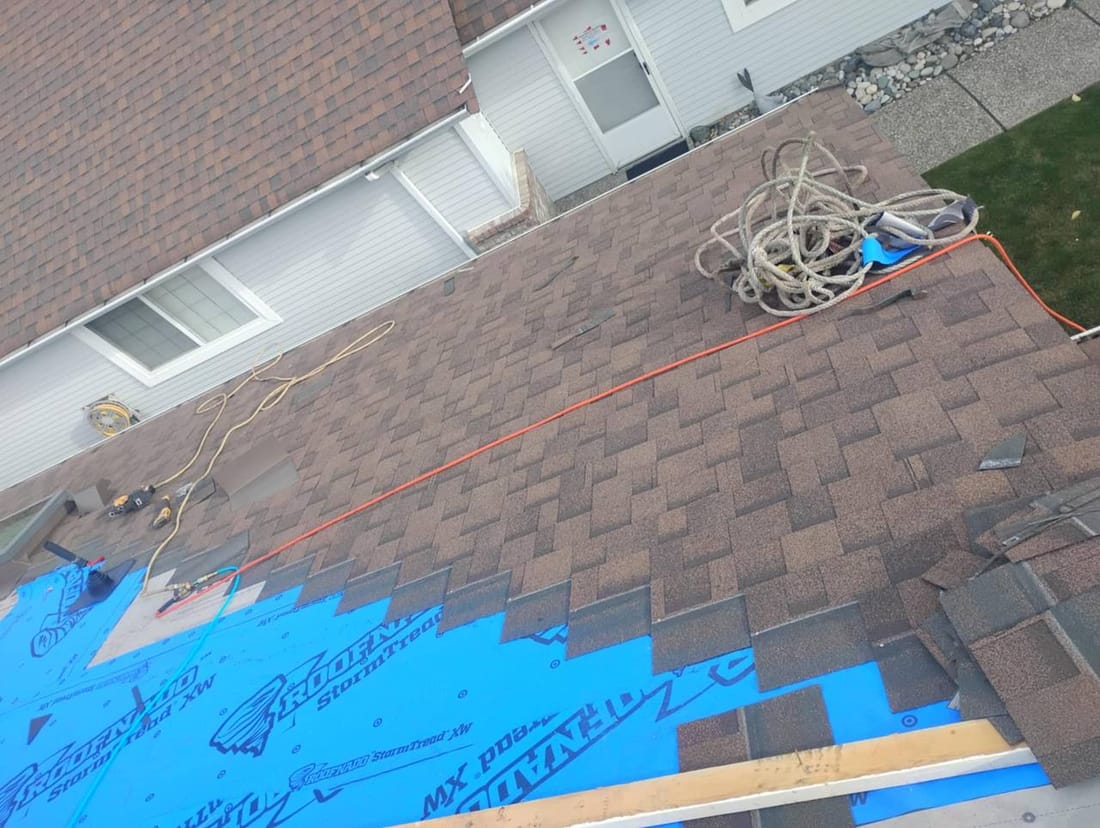 Brown architectural shingle installation mid-job by Fraser Roofing showing clean coursing and proper overlap on a Fraser Valley residential roof