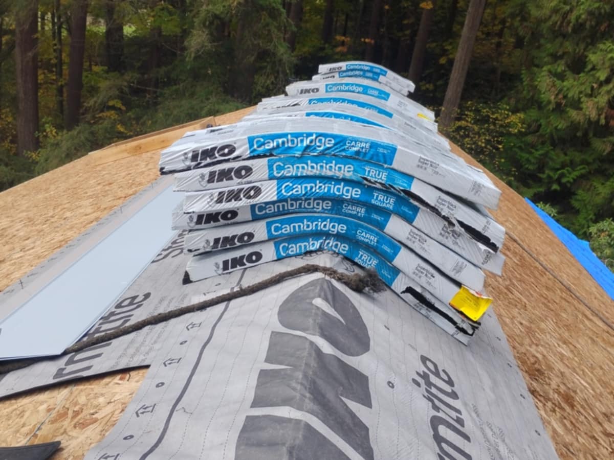 IKO Cambridge shingle bundles stacked on roof ridge over OSB deck and synthetic underlayment in Fraser Valley - shingle brands