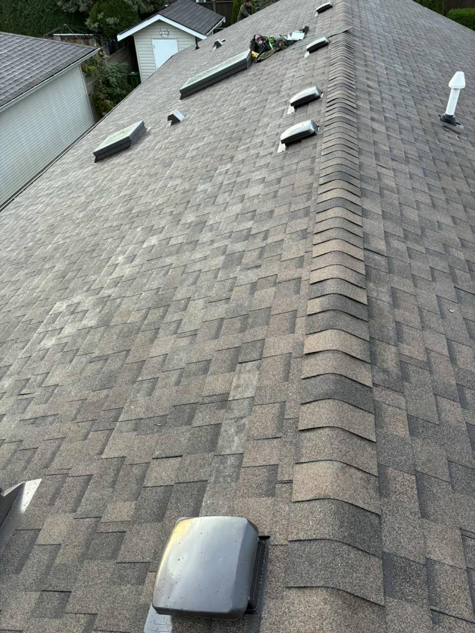 Completed asphalt shingle roof with ridge cap and multiple vents during final inspection in Chilliwack by Fraser Roofing, the kind of quality installation backed by a strong workmanship warranty