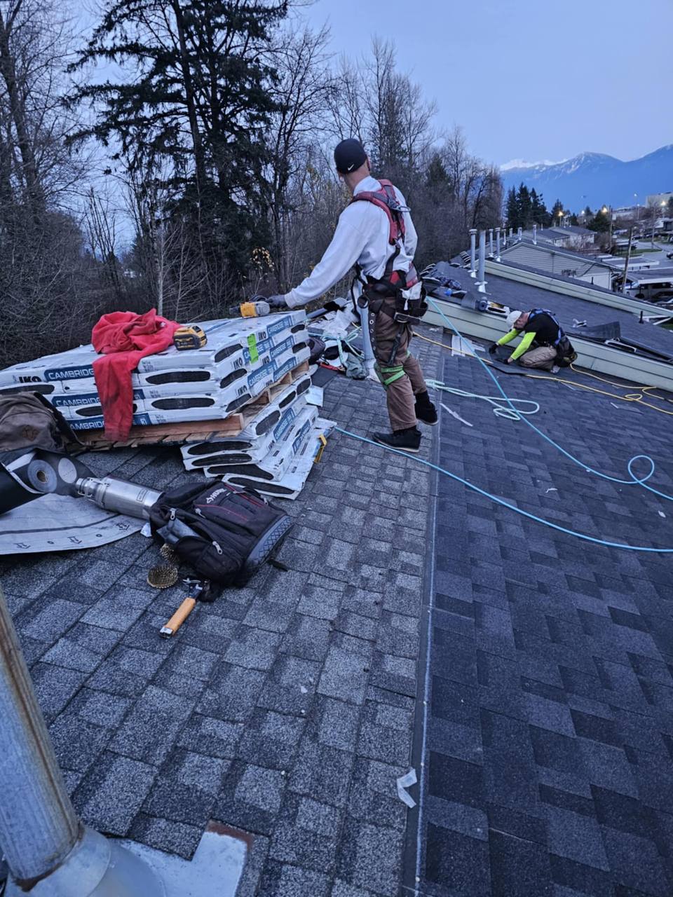 Fraser Roofing crew working on a complex bundle of shingles during a residential roof installation in the Fraser Valley with mountain views