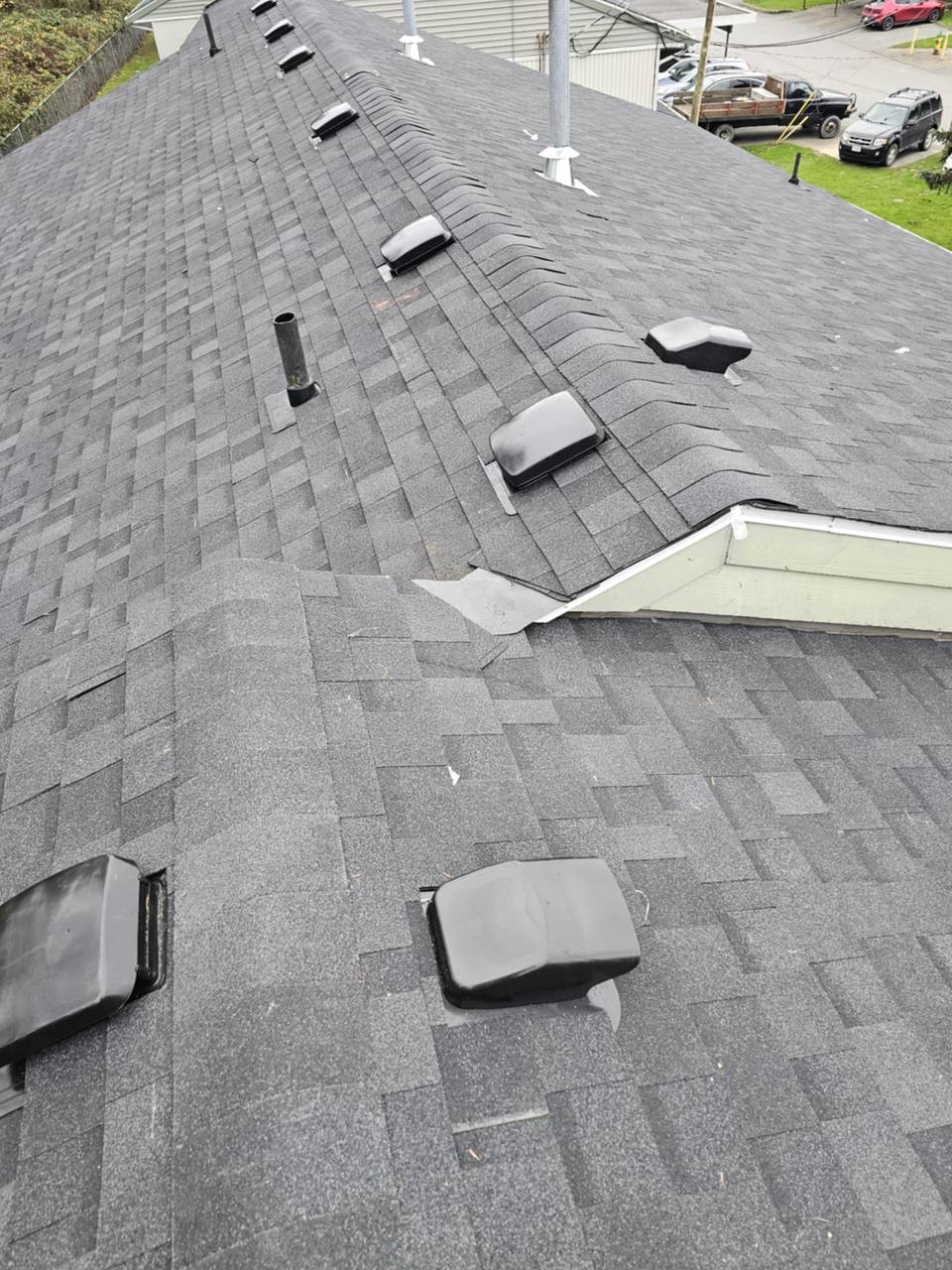 Completed charcoal architectural asphalt shingle re-roof with multiple box vents and metal flashing at roof junction on a residential home in Chilliwack BC by Fraser Roofing