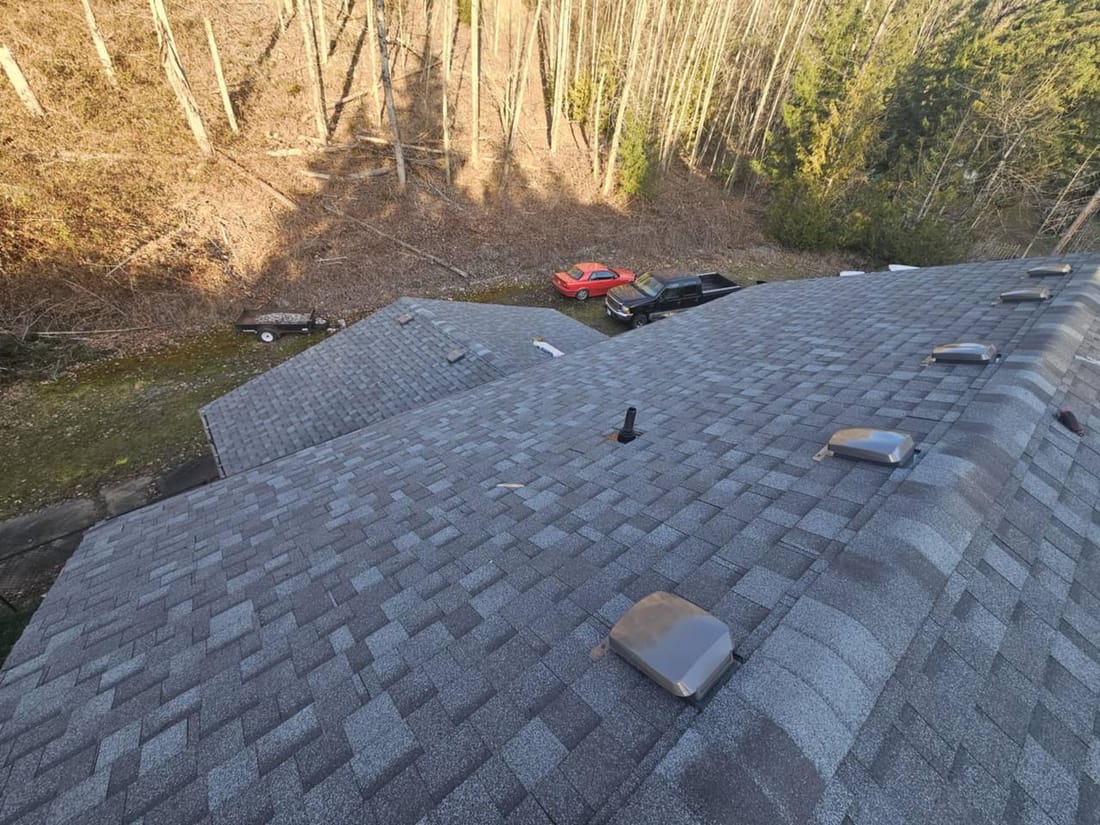Completed charcoal grey architectural asphalt shingle roof with box vents and ridge cap viewed from peak in Chilliwack BC - asphalt roofing option