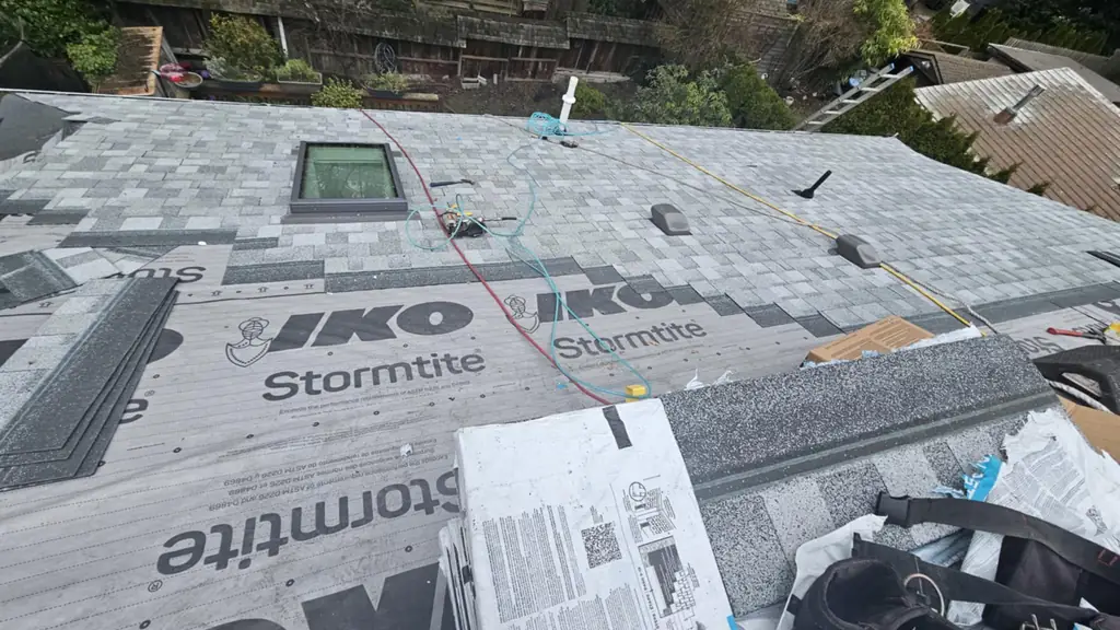 An on-roof close shot of IKO Stormtite synthetic underlayment installed with its branding clearly visible, next to a skylight. Fraser Roofing
