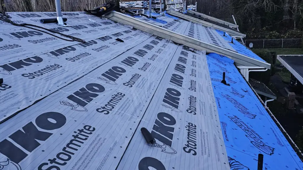 Looking down a long ridge on a multi-unit roof freshly covered in IKO Stormtite synthetic underlayment. Fraser Roofing
