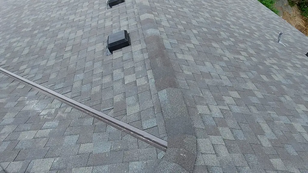 An elevated view looks over a finished grey architectural shingle roof with several roof vents along a ridge line. Fraser Roofing