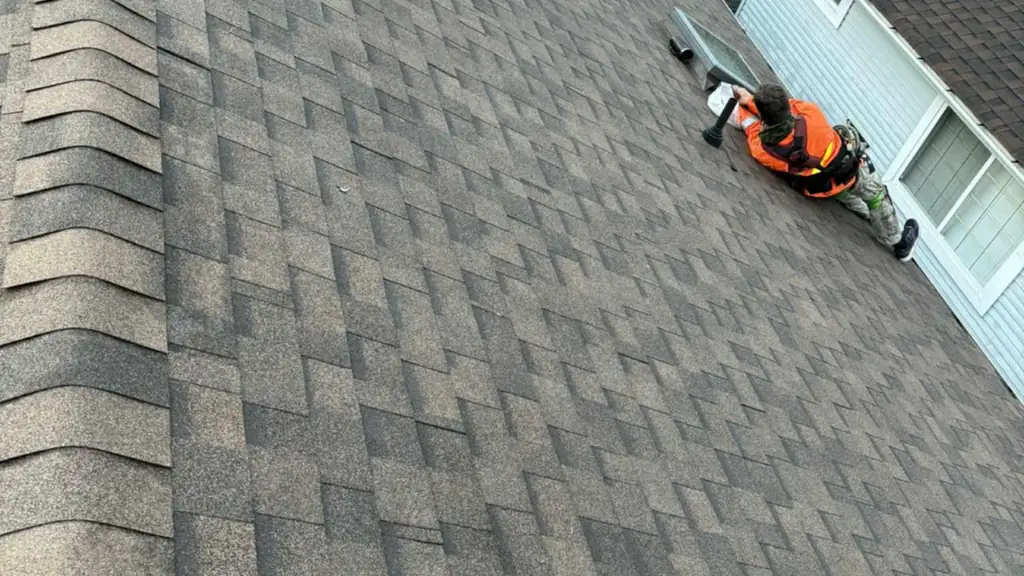 An overhead view along a tan asphalt shingle roof with two roof vent stacks and a skylight. Fraser Roofing
