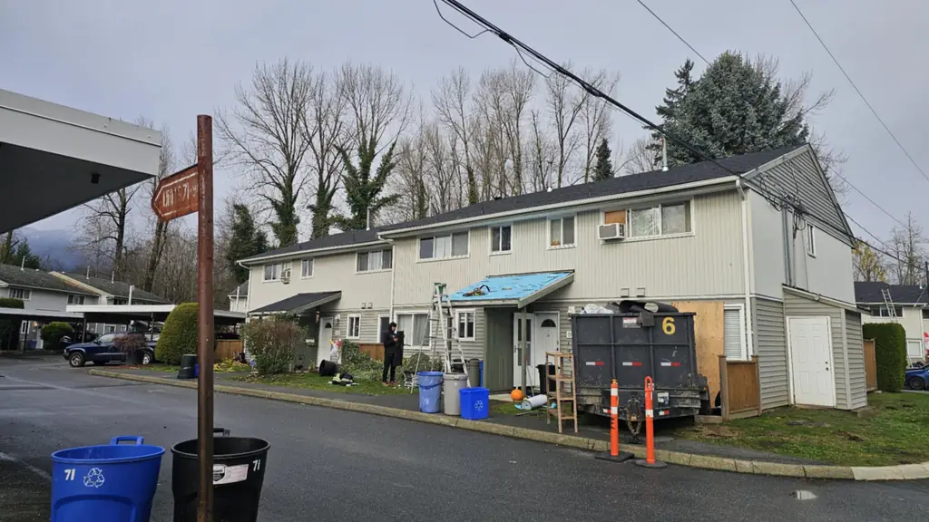 Street-level view of a townhouse row on a grey, damp day. Fraser Roofing