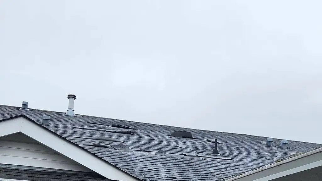 Townhouse roof with wind-damaged and missing asphalt shingles. Fraser Roofing