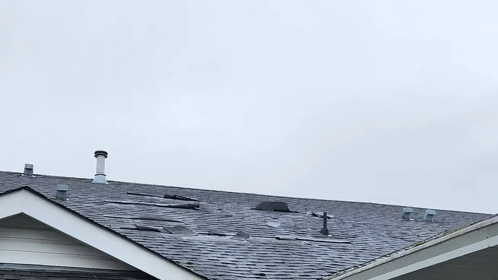 Townhouse roof with wind-damaged and missing asphalt shingles. Fraser Roofing
