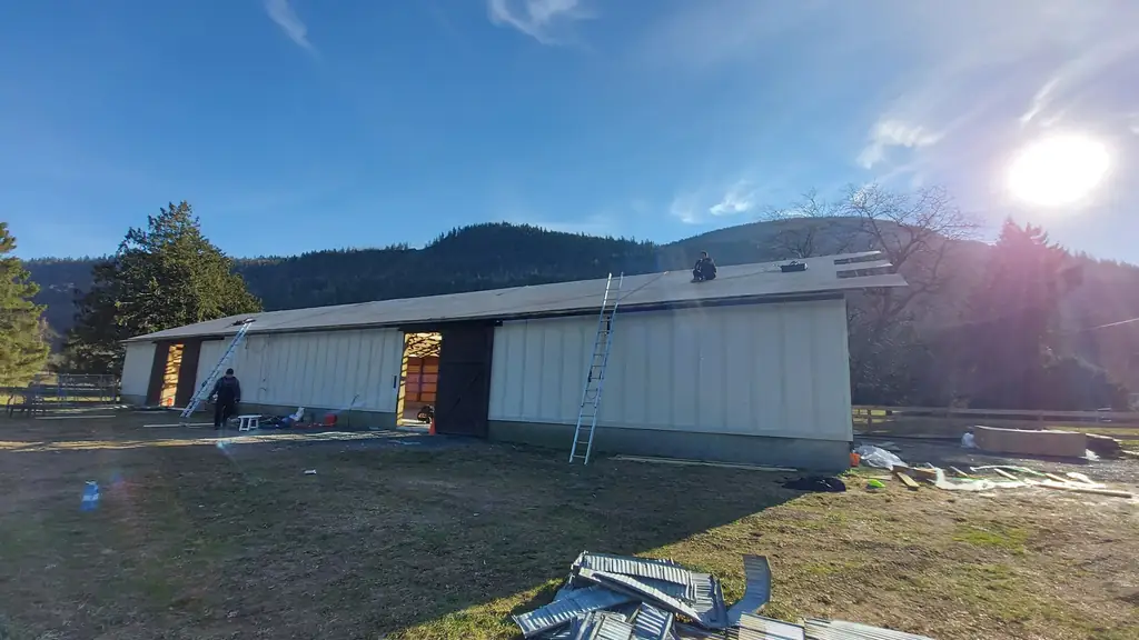 Wide view of a light-coloured steel pole barn under construction. Fraser Roofing