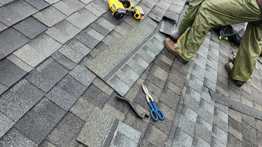 Roofer replacing wind-damaged shingles on a townhouse roof. Fraser Roofing