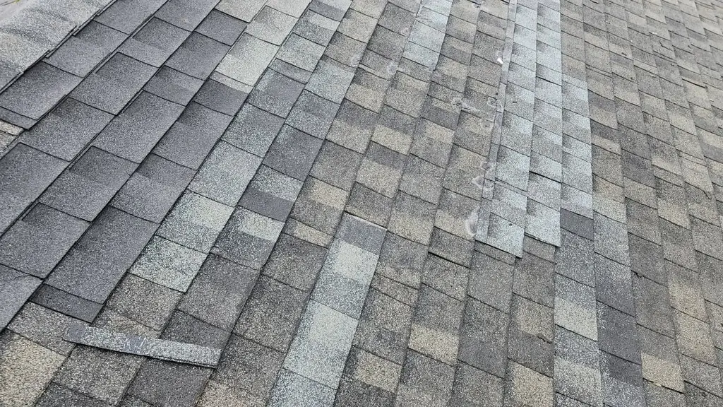 Townhouse roof slope with new replacement shingles after a wind damage repair. Fraser Roofing