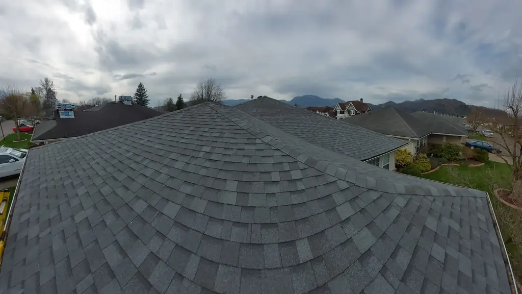 Wide panorama across a large finished grey hip roof with a distinctive fan/scalloped shingle pattern at the hips. Fraser Roofing
