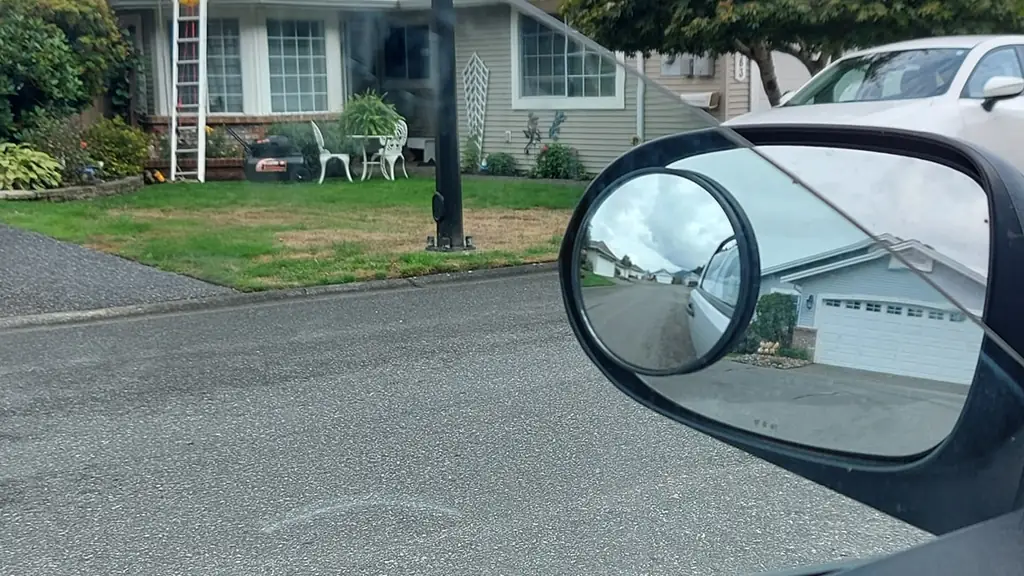 A photo taken from inside a vehicle, framed by the car's window pillar, side mirror and door handle in the foreground. Fraser Roofing
