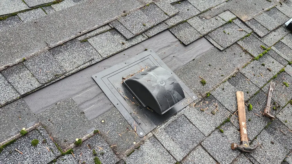 A close, on-roof shot of a grey asphalt shingle roof with a freshly installed round plastic roof vent and black rubber boot near the top of frame. Fraser Roofing