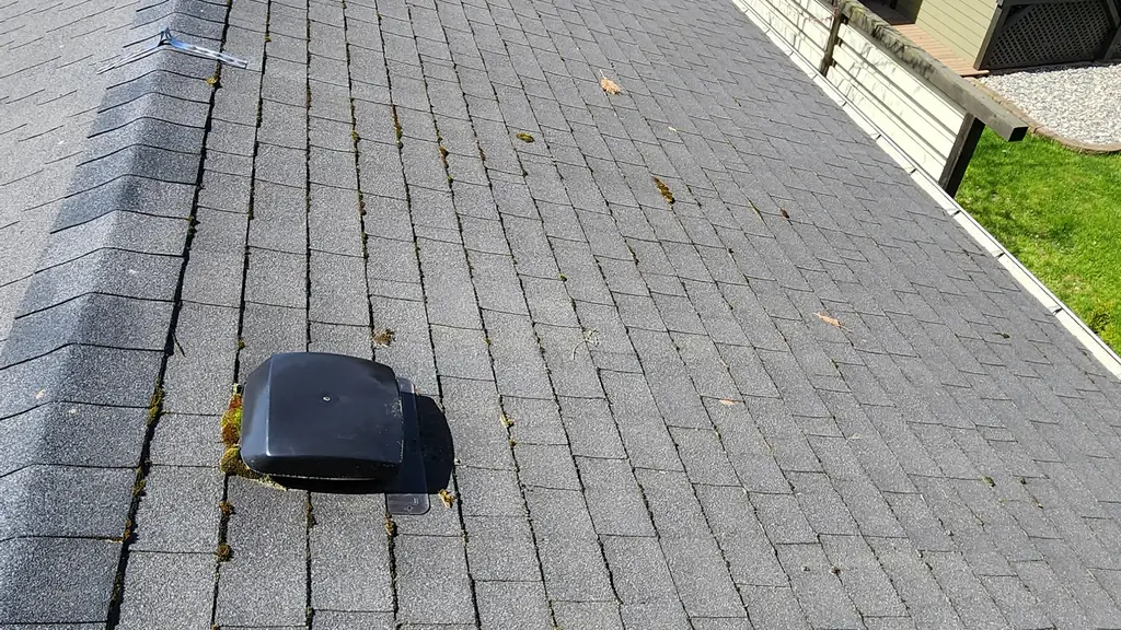 A view down a grey asphalt shingle roof ridge shows a black roof vent and metal jack. Fraser Roofing
