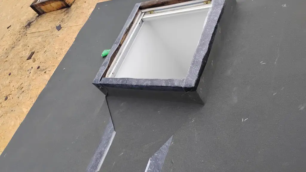 A close-up of two new skylight curbs being flashed with grey membrane on top of plywood decking. Fraser Roofing