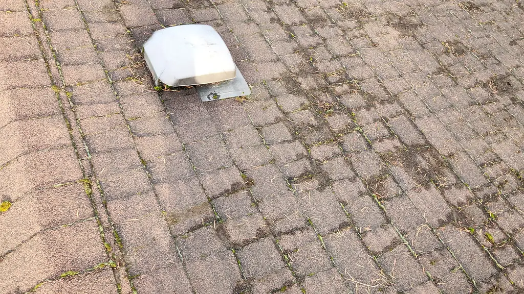A close-up shows a low-profile white plastic roof vent set into an aged asphalt shingle roof, with scattered patches of moss nearby. Fraser Roofing