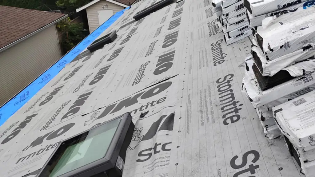 A wide on-roof shot showing grey IKO Stormtite synthetic underlayment fully covering the roof deck. Fraser Roofing