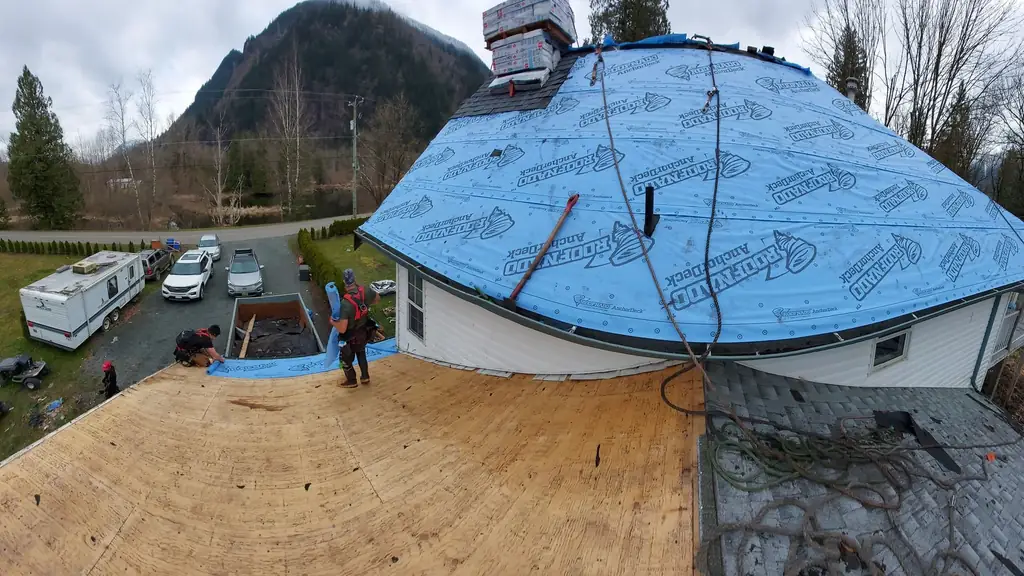 A wide shot of a barrel/dome-shaped roof section covered in blue-and-white printed synthetic underlayment. Fraser Roofing