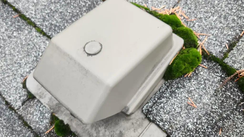 Extreme close-up of a gray plastic roof vent cap sitting on gray asphalt shingles. Fraser Roofing