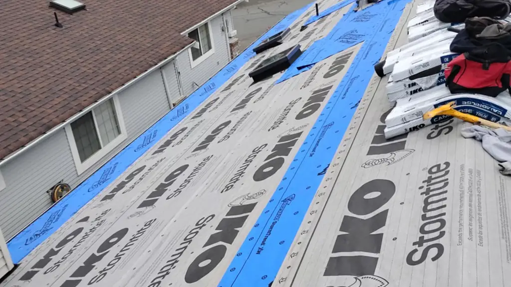 High overhead shot down a roof slope covered in IKO Stormtite underlayment with two blue synthetic strips running down it and two skylights punched. Fraser Roofing