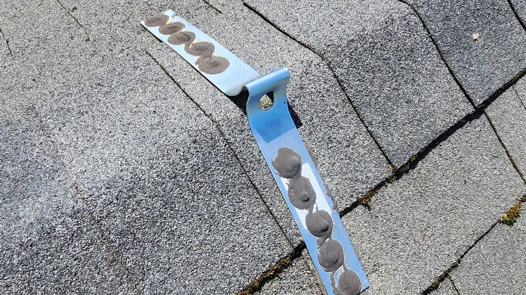 A close-up shows a bent metal mounting strap with several dabs of grey roofing sealant covering screw heads. Fraser Roofing