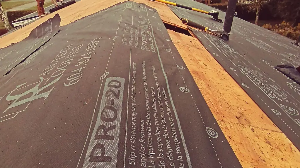 Close view along a roof slope where synthetic underlayment printed 'PRO-20' has been rolled out and stapled down. Fraser Roofing
