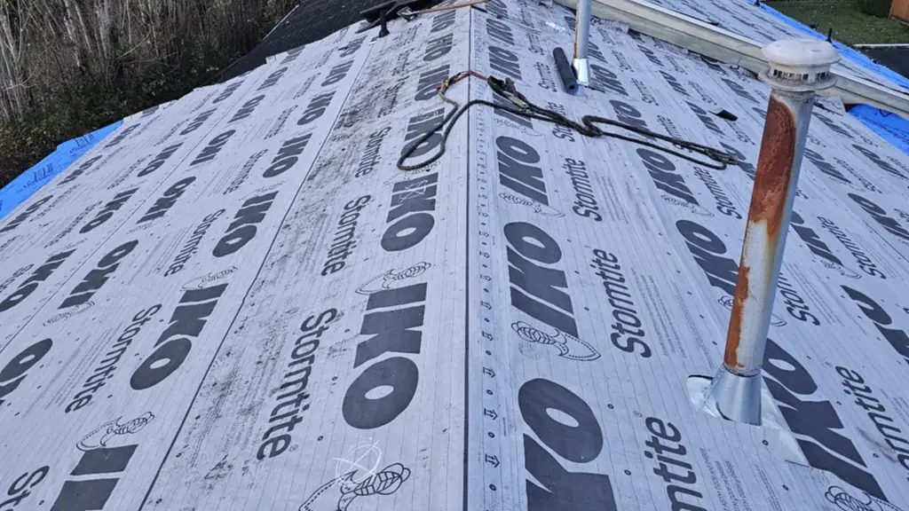 Overhead view straight down a ridge covered in IKO Stormtite underlayment with a rusted galvanized vent stack and a newer plumbing vent boot nearby. Fraser Roofing