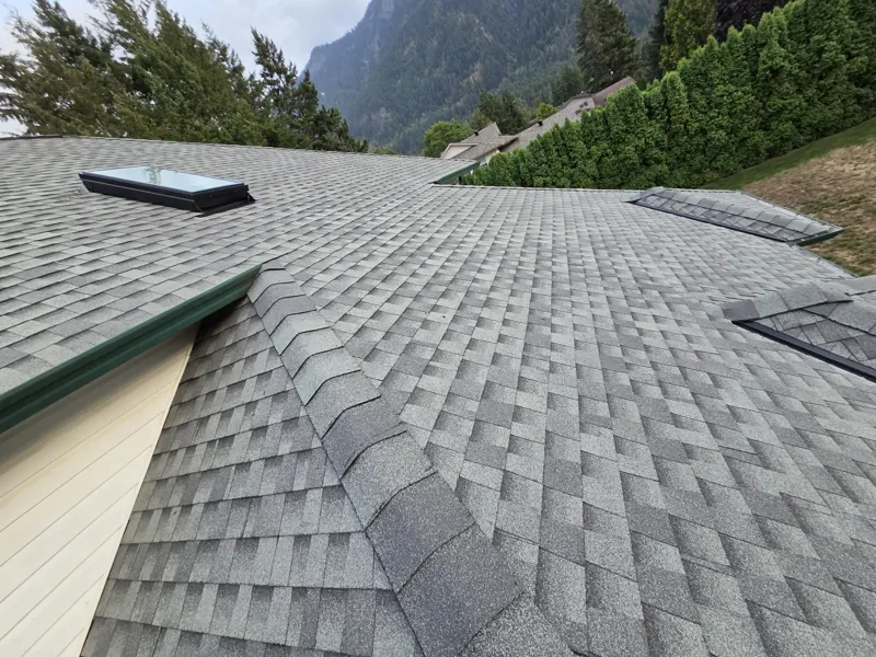 Finished shingle roof with skylights, mountain behind
